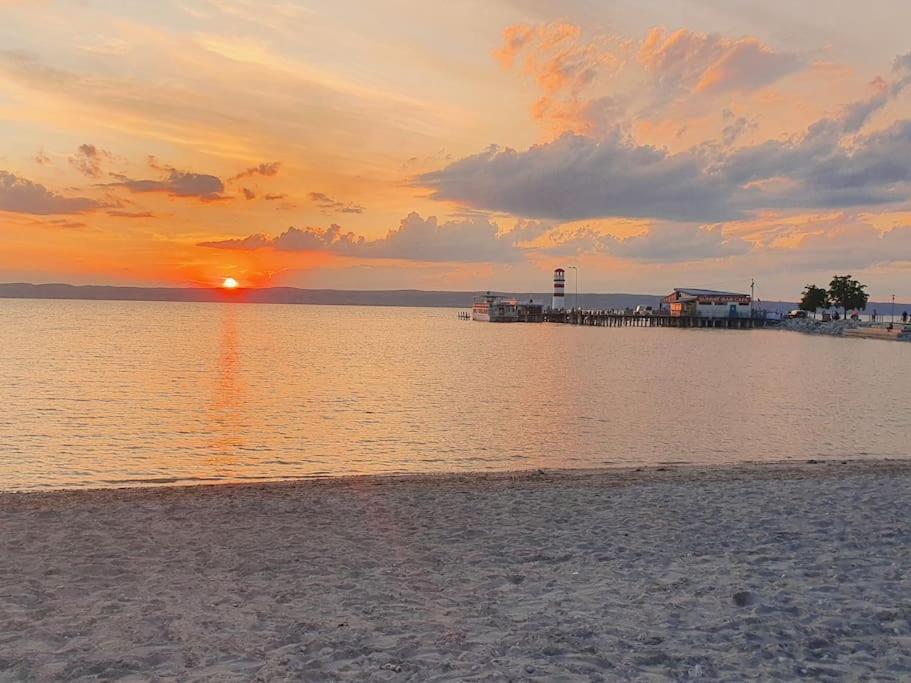 um pôr-do-sol sobre uma praia com um cais e o oceano em Mareli Neusiedler Stadthaus em Neusiedl am See