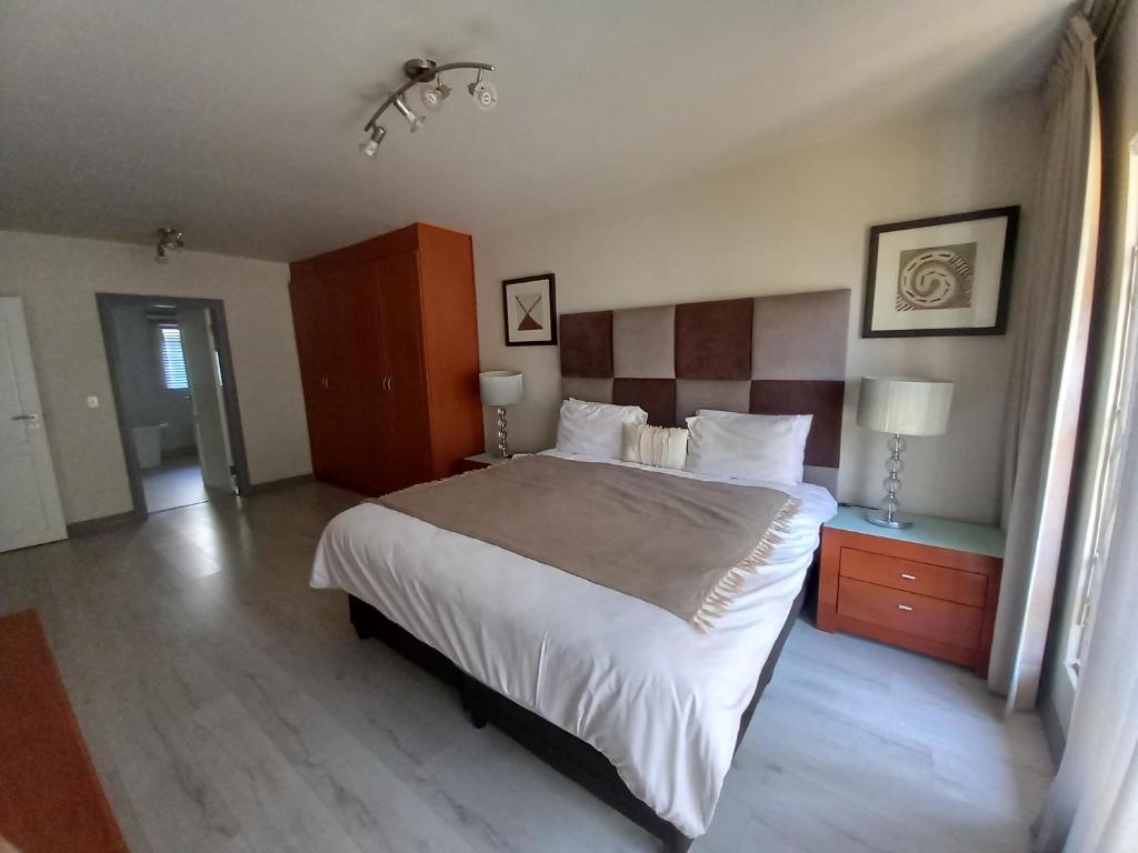 Un dormitorio con una cama grande y dos mesitas de noche. en Mount Royal 02 Large 3 bedroom Ground floor apartment with Garden, en Johannesburgo