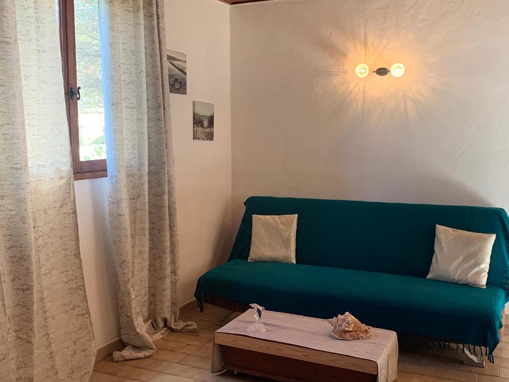 uma sala de estar com um sofá verde e uma mesa em Gîte à Poggiale de Figari em Figari