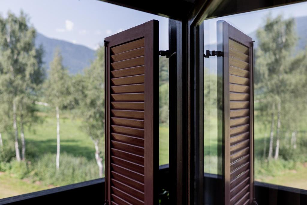 une fenêtre ouverte avec vue sur la forêt dans l'établissement Rooms Kronblick, à San Lorenzo di Sebato