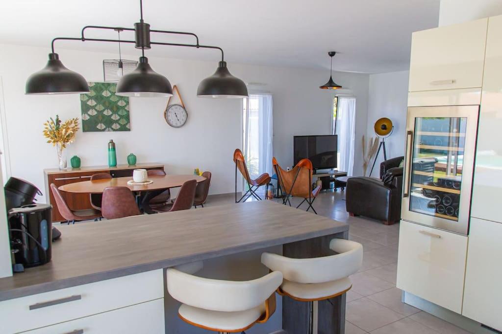 a kitchen and living room with a table and chairs at VILLA avec PISCINE chauffée trois chambres in Saint-Sulpice-de-Royan