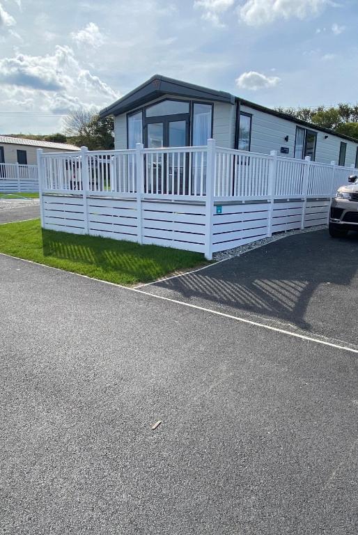 a house with a white fence next to a road at Riverwood Lodge in Newquay Bay Resort