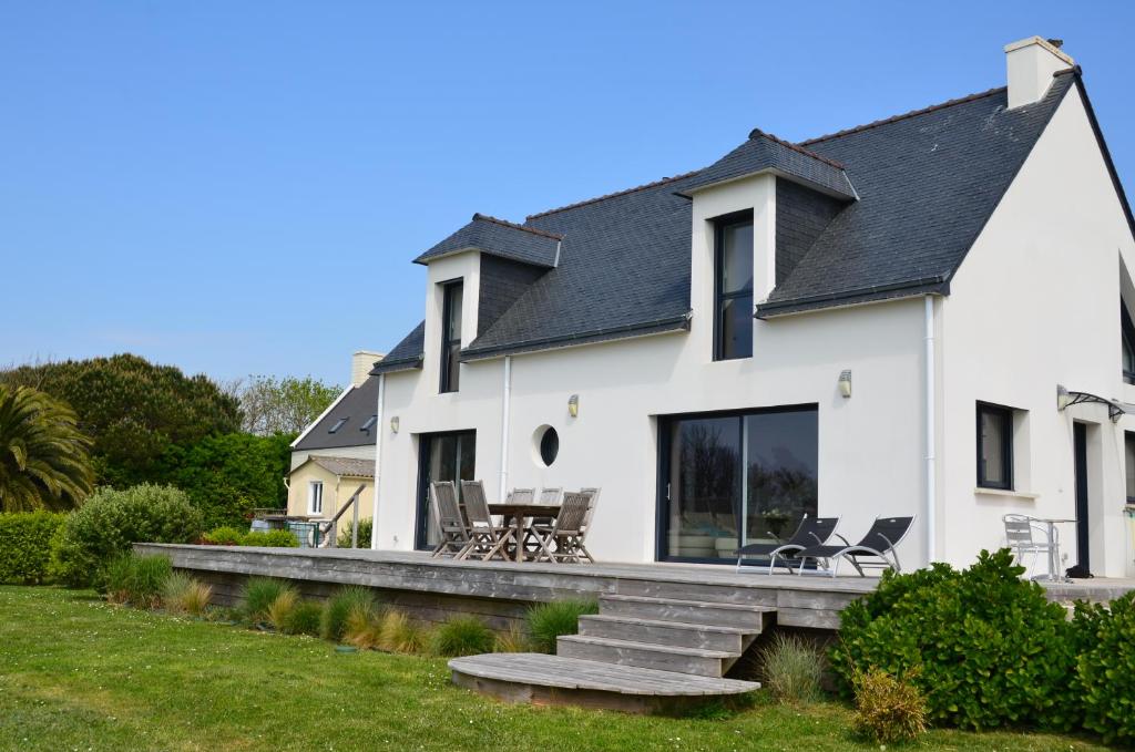 een wit huis met een veranda en een patio bij La Magnifique Villa à 500m de la plage in Plozévet