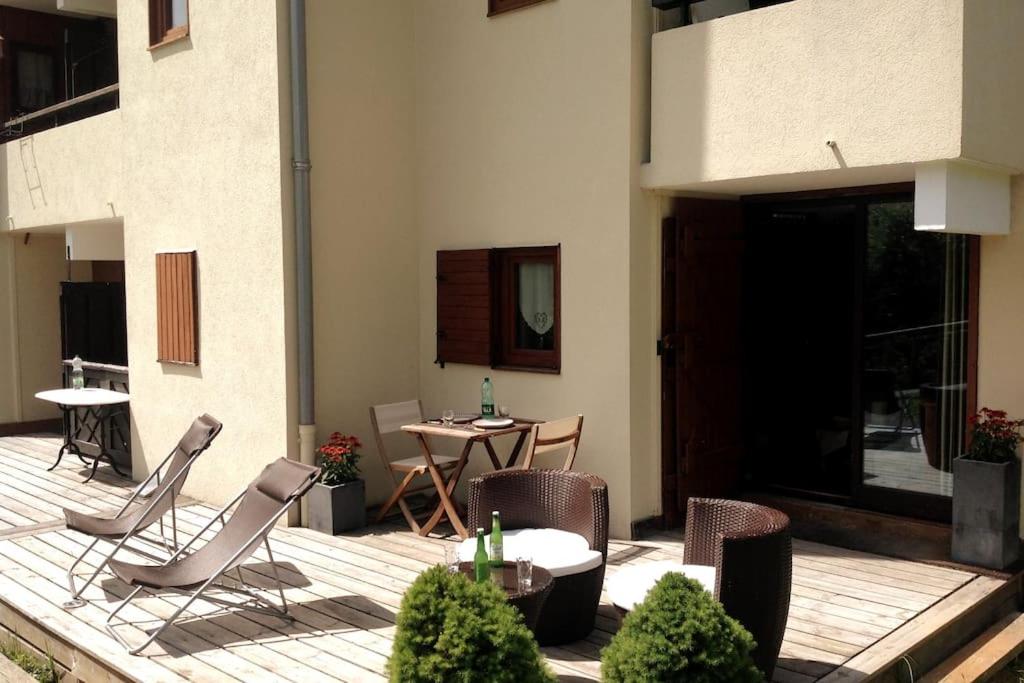 patio z krzesłami i stołem w budynku w obiekcie Appartement la Clusaz avec terrasse sur les pistes de ski w mieście Manigod