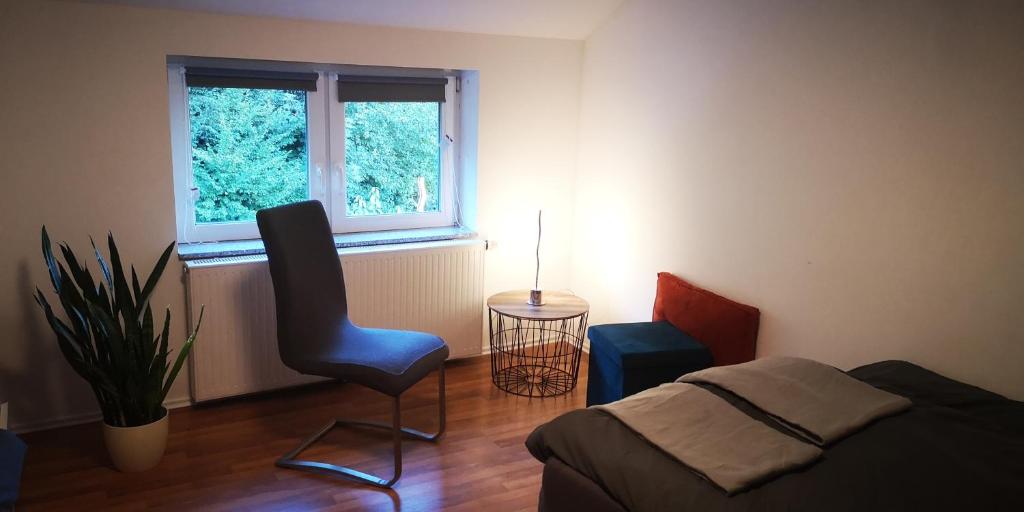 a bedroom with a bed and a chair and a window at SLEEP WELL Apartments, FEWO Falkenburg in Detmold