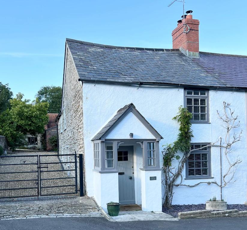 a white building with a door and a staircase at Hurst cottage, a cosy 2 bed cottage in Dorset in Stalbridge