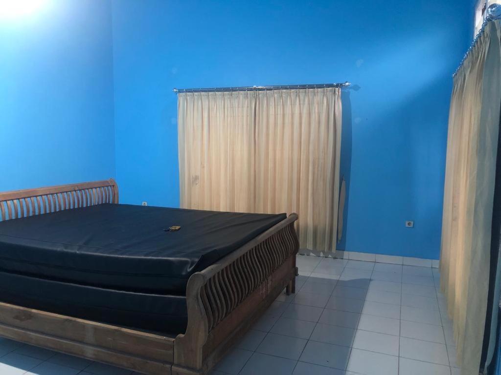 a bed in a room with a blue wall at Bandongan Guest House 