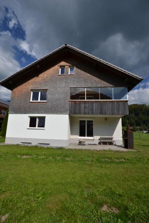 uma casa com uma varanda no topo de um campo de relva em Ferienwohnung Känzeleblick em Bezau