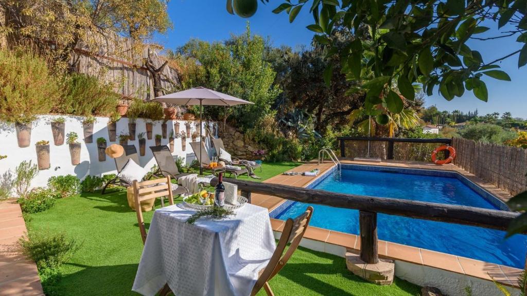 モンダにあるCasa Guajar Monda by Ruralidaysのテーブルとスイミングプールのある裏庭