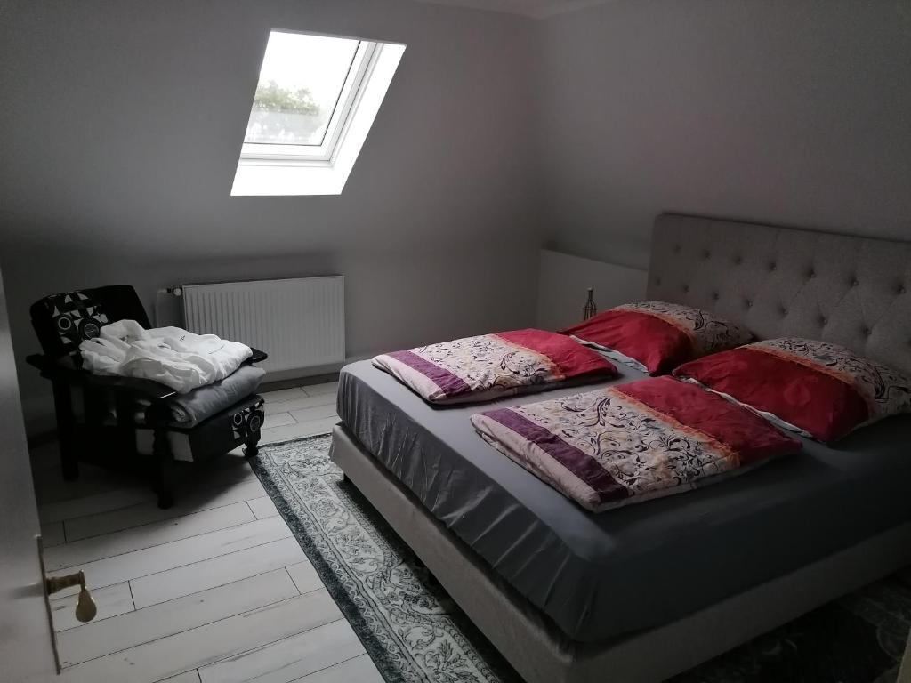 Schlafzimmer mit einem Bett mit roten Kissen und einem Fenster in der Unterkunft Haus Lupo am Kanal in Castrop-Rauxel