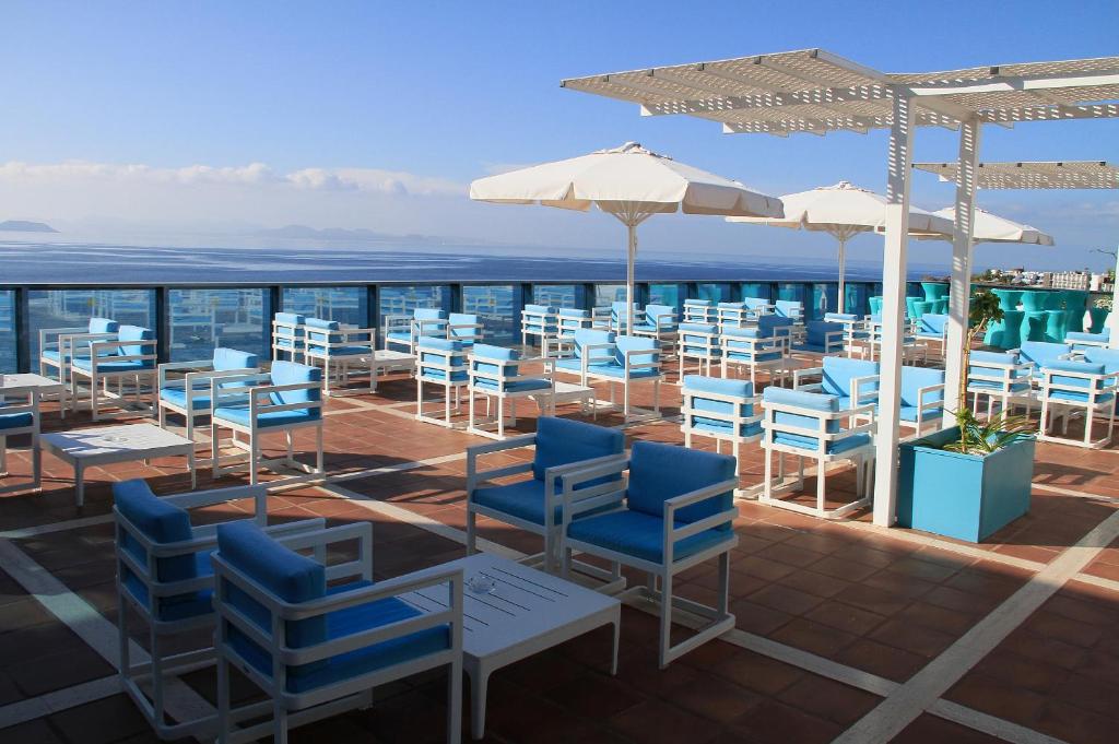 a patio with blue chairs and tables and umbrellas at Sandos Papagayo in Playa Blanca