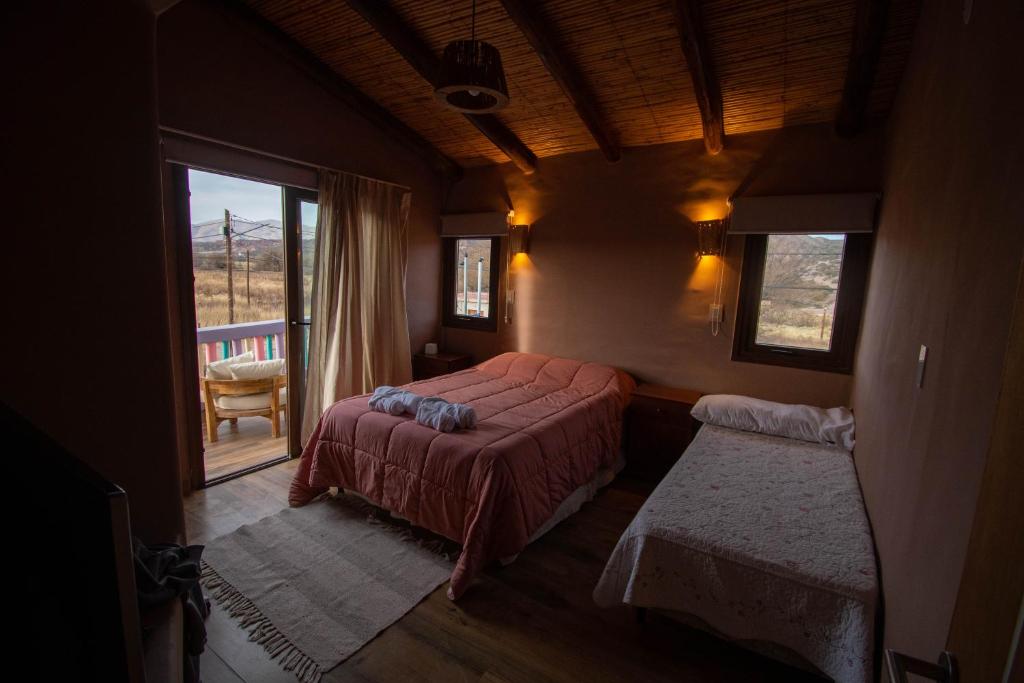 ein Schlafzimmer mit einem Bett und einem großen Fenster in der Unterkunft Tikay Humahuaca Refugio de Tierras in Humahuaca