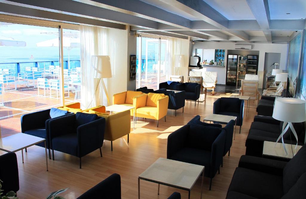 a waiting room with chairs and tables and windows at Sandos Papagayo in Playa Blanca