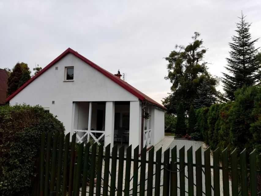 ein weißes Haus mit einem Zaun davor in der Unterkunft Dom nad jeziorem Blisko E-ga. Idealny na Wakacje, na ryby. Pochylnie. 