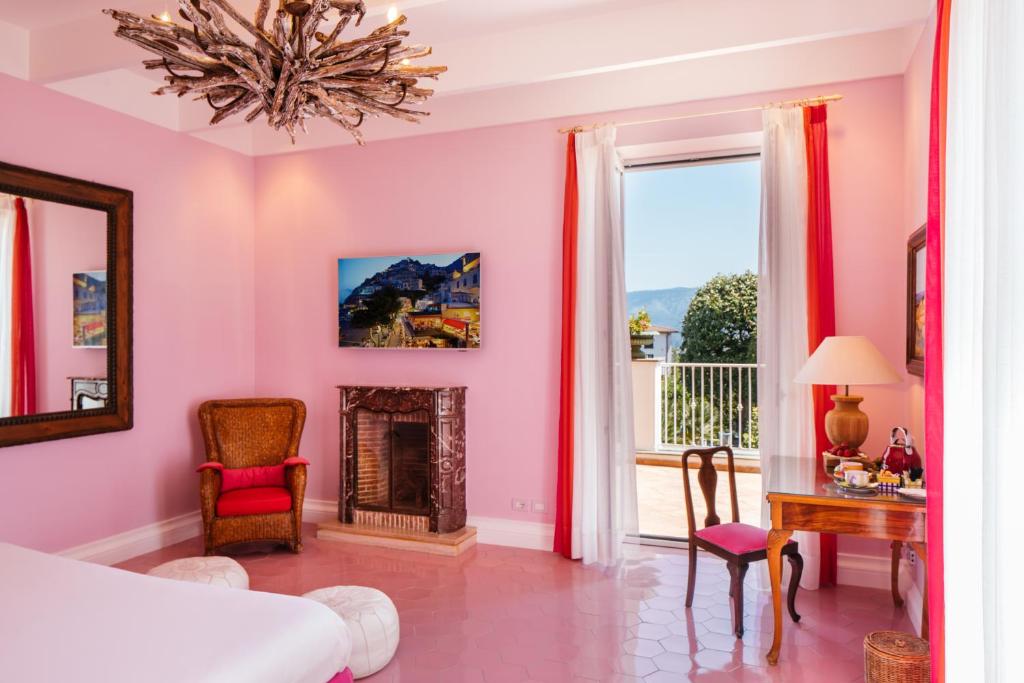 Dormitorio rosa con cama y chimenea en Boutique Hotel Don Alfonso 1890, en SantʼAgata sui Due Golfi