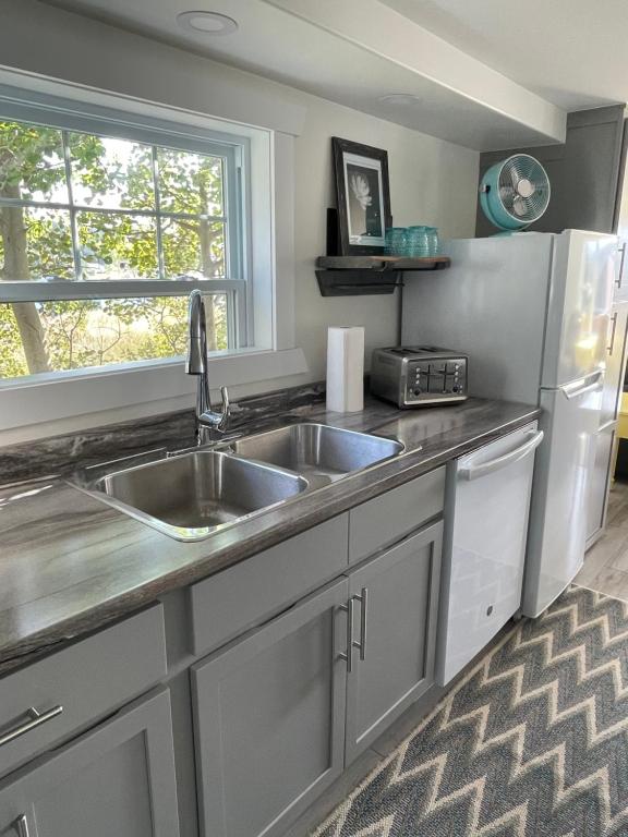 a kitchen with a sink and a refrigerator at Squid Cove Cottage in Pilleyʼs Island
