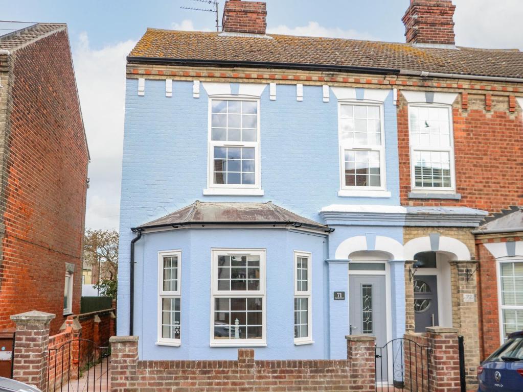 una casa azul con ventanas blancas en una calle en The House in Gorleston, en Great Yarmouth
