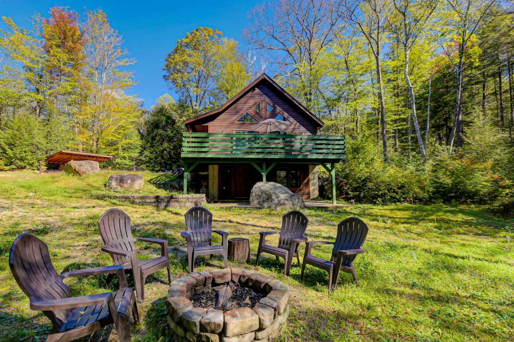 a group of chairs around a fire pit in front of a cabin at Artist Brook Escape in North Conway