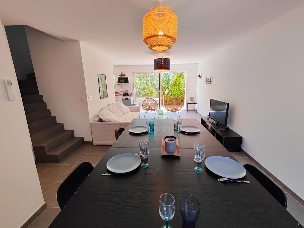 uma mesa de jantar com pratos e copos de vinho em Villa Vias Plage neuve em Vias