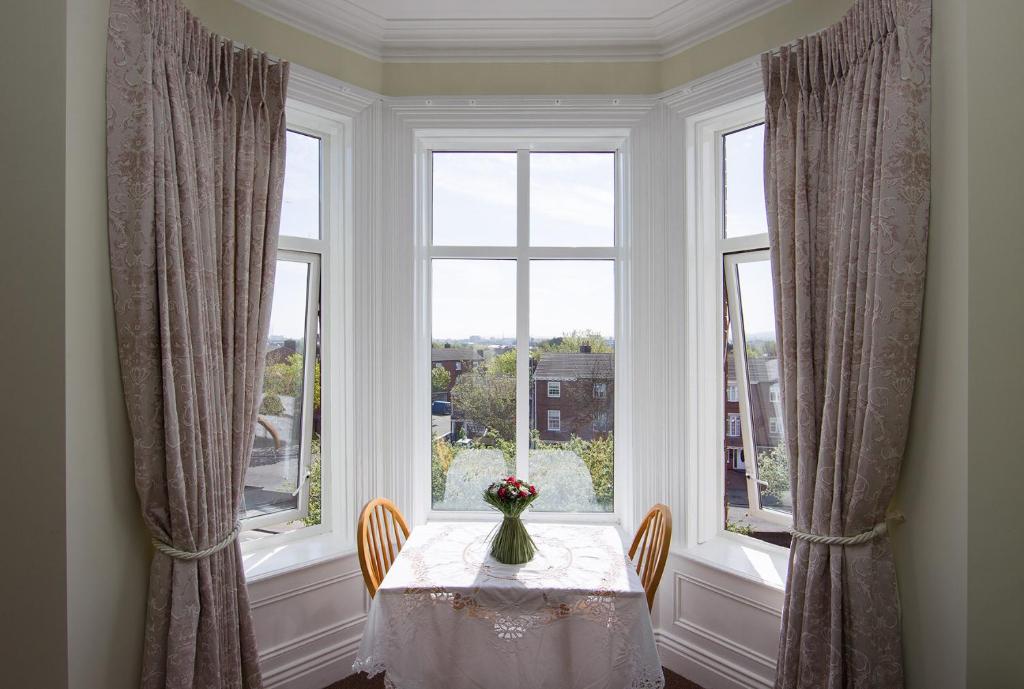 uma mesa com um vaso de flores sobre ela em uma janela em Glencourt Apartments em Dublin