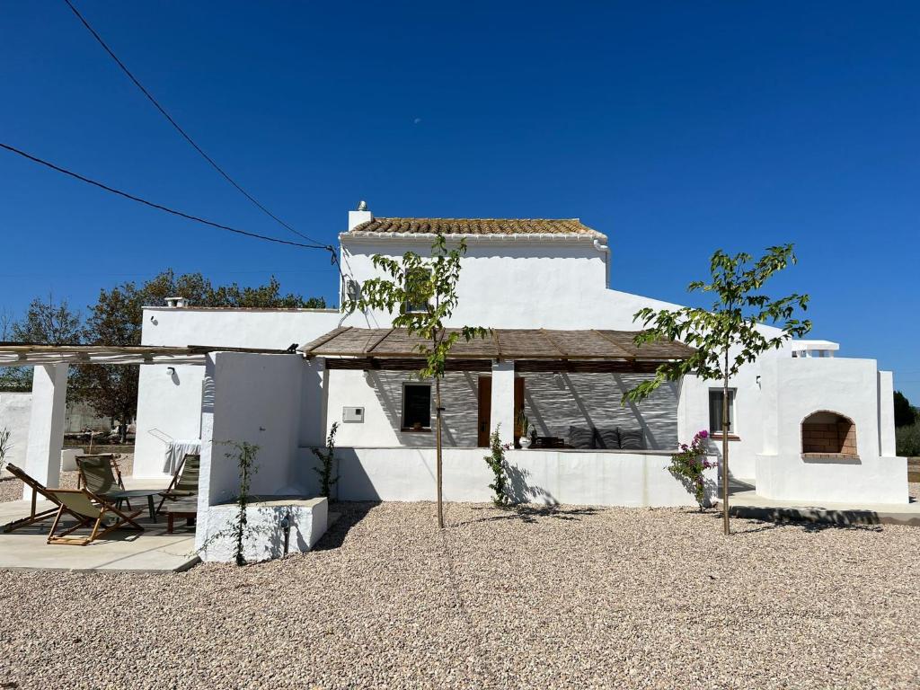 Casa blanca con mesa y silla en Mas Midó, en Sant Jaume d'Enveja