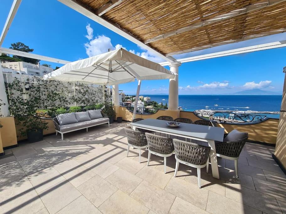 um pátio com uma mesa, cadeiras e um guarda-sol em La Spiga em Capri