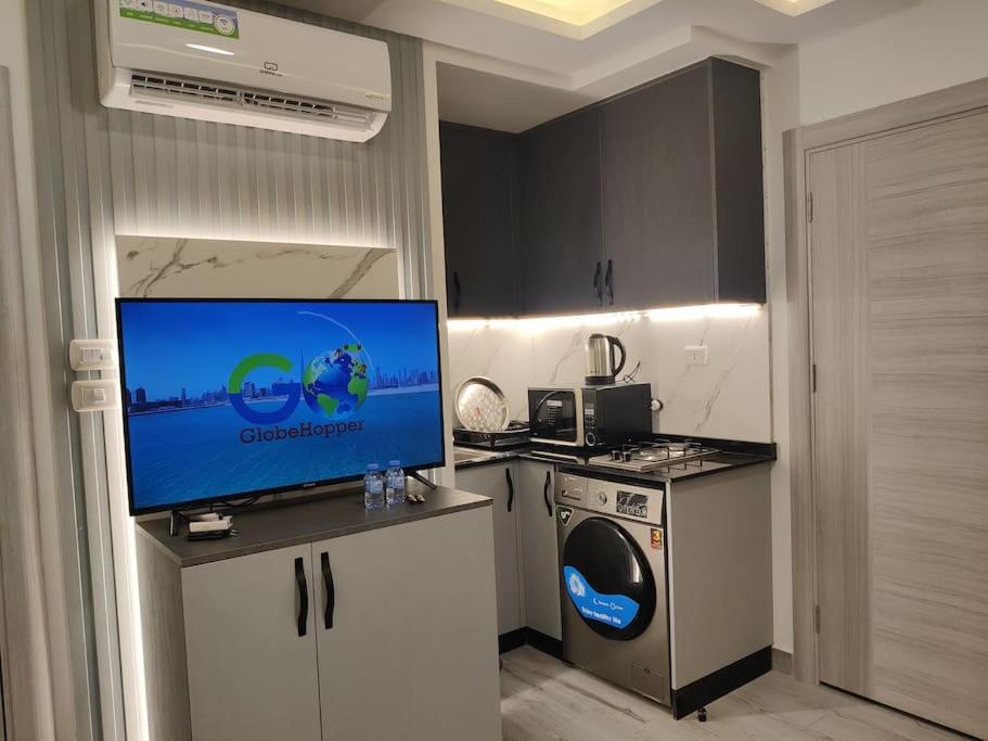 a kitchen with a tv and a washing machine at (41)m luxury room royal view near all services in Ash Shumaysānī