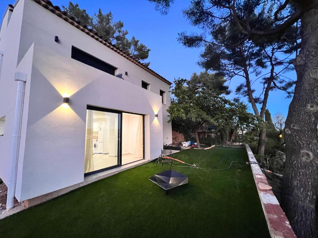 - une vue sur l'extérieur d'une maison blanche avec une pelouse verte dans l'établissement Appartement des Oliveraies, à La Valette-du-Var