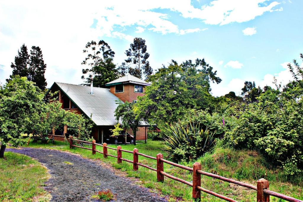 una casa de madera con una valla junto a un camino de tierra en Cabanas de Monasterio, en Puerto Clocker