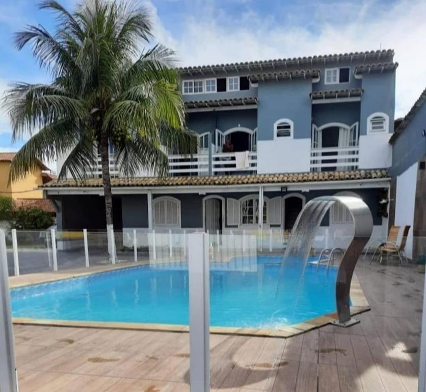 a villa with a swimming pool in front of a building at Suítes Moinho in Cabo Frio