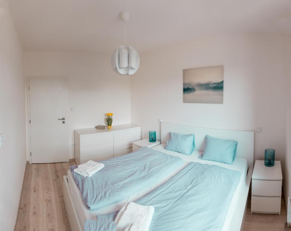 biała sypialnia z dużym łóżkiem z niebieską pościelą w obiekcie Apartmán Sjezdovka w mieście Kašperské Hory