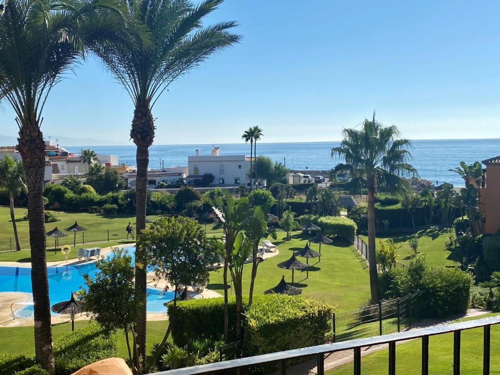 uma vista para a piscina e para o oceano a partir da varanda de um resort em Los Granados de la Duquesa em San Luis de Sabinillas