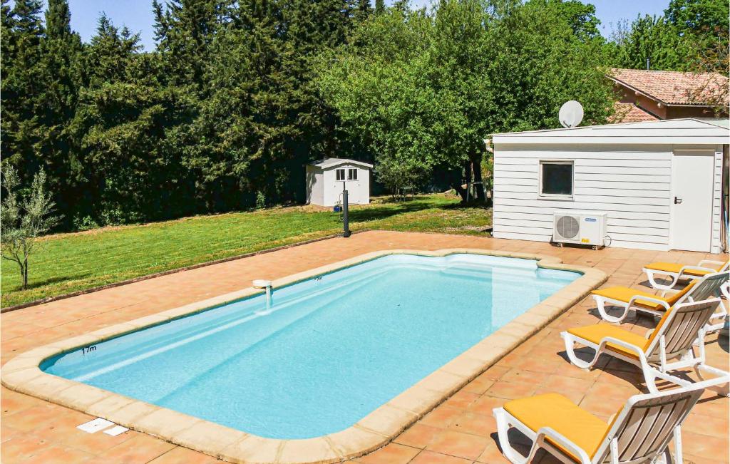 a swimming pool with two chairs and a house at Nice Home In Ferrires-poussarou With Kitchen in Ferrières-Poussarou