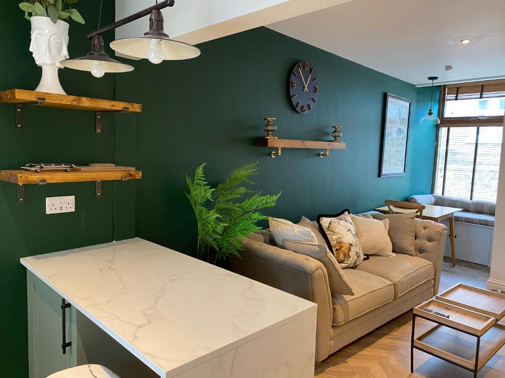 uma sala de estar com paredes verdes e um sofá em Luxurious one-bedroom seaside apartment em Eyemouth