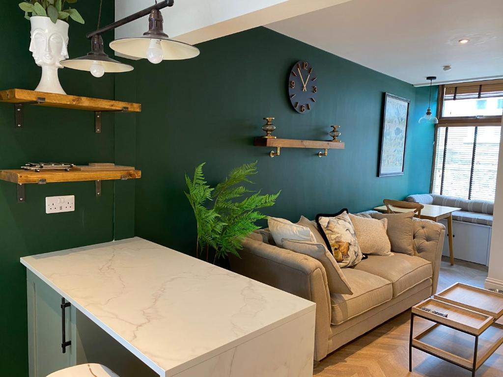 a living room with green walls and a couch at Ridley's Place modern one-bedroom seaside apartment in Eyemouth