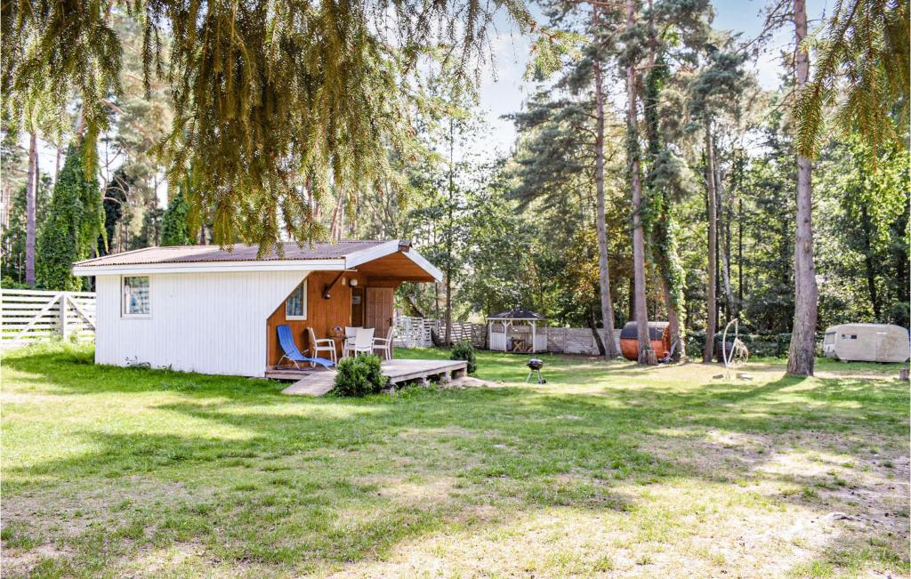 a small white shed in a yard with trees at Awesome Home In Pobierowo With Kitchen in Pobierowo