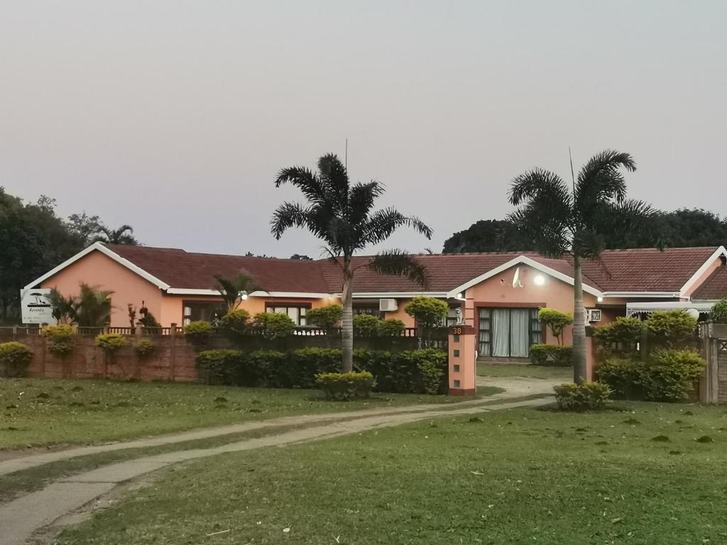 een roze huis met palmbomen ervoor bij Mavundla guest house in Richards Bay