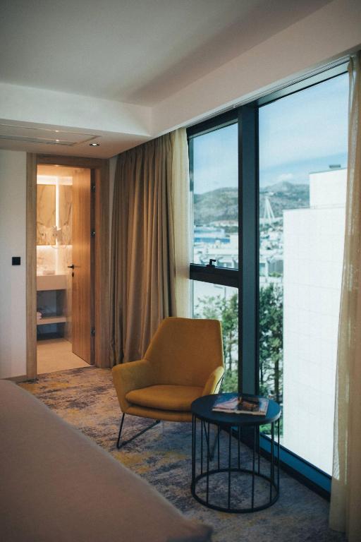 a room with a bed and a chair and a window at City Hotel Dubrovnik in Dubrovnik