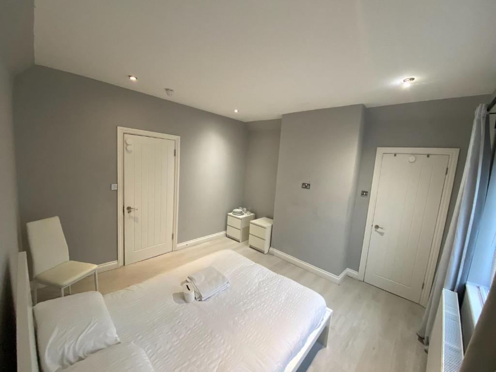 a bedroom with a white bed and a chair at Large house close to Greenwich in Eltham