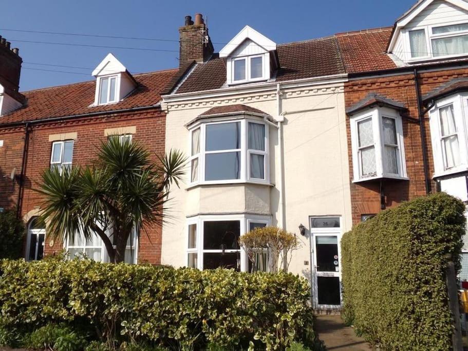 una casa blanca con una palmera delante de ella en The Halt, Sheringham - 2x car spaces, Family friendly holiday home close to beach, en Sheringham