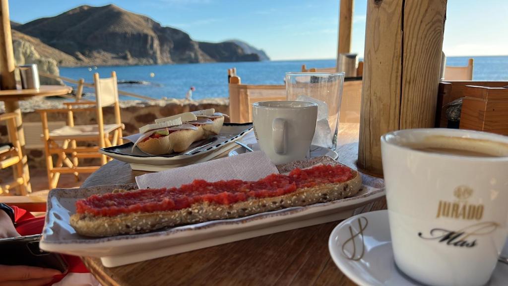 una mesa con un perrito caliente y una taza de café en Isleta 5, en La Isleta del Moro