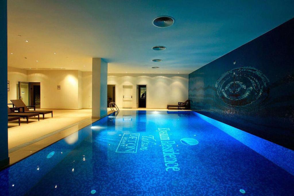 a large swimming pool with blue lighting in a building at Taksim Elysium Residence in Istanbul