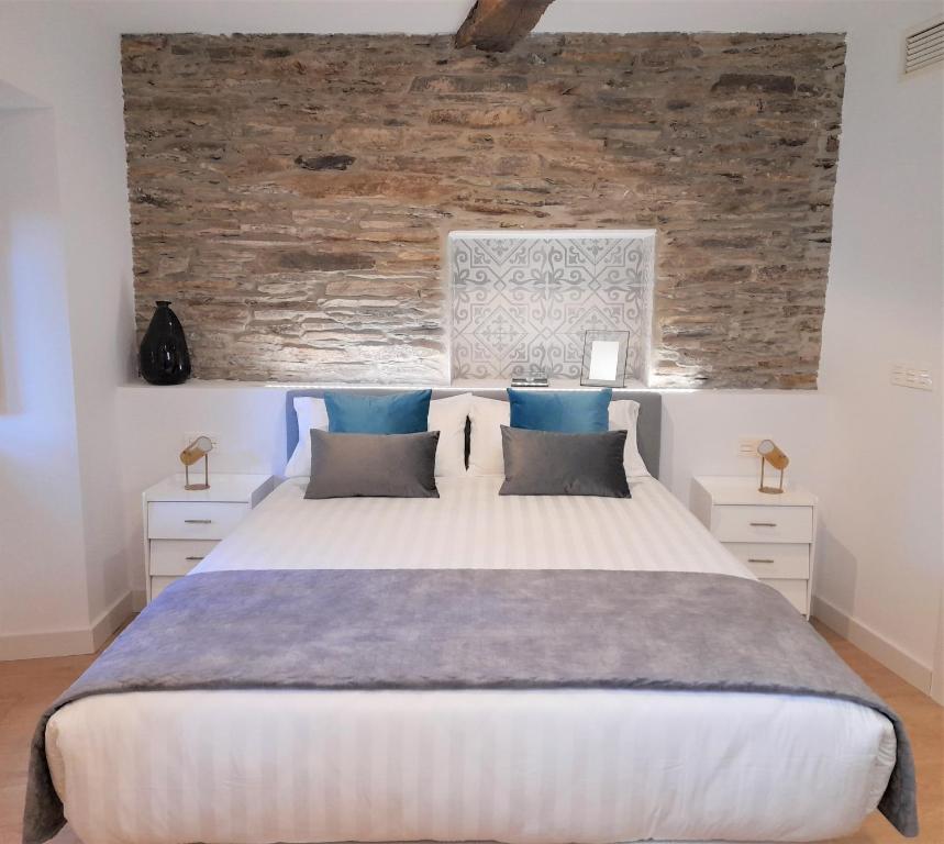 um quarto com uma grande cama branca com almofadas azuis em Apartamento con encanto en centro histórico Lugo -TineriaLucusHome em Lugo