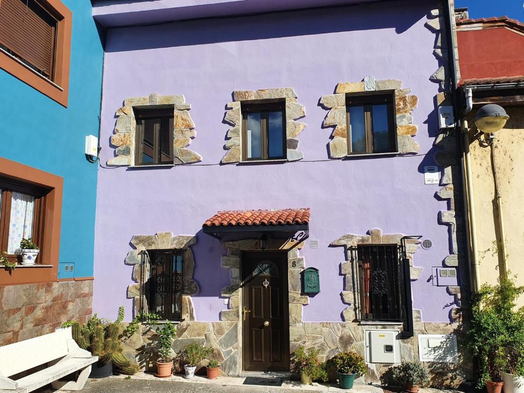 Un bâtiment violet avec des fenêtres et une porte dans l'établissement Casa Rural Puerta del Gamoniteiru, à Pola de Lena
