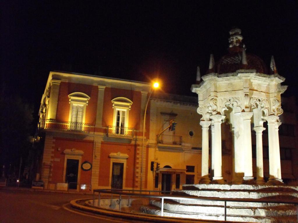 un edificio con una fuente delante de él por la noche en Palazzo Osanna, en Nardò