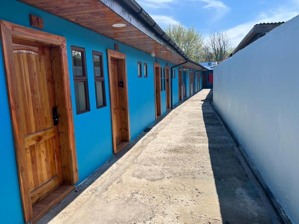 une rangée de bâtiments bleus avec portes en bois dans l'établissement Hospedaje Santa Barbara, à Santa Bárbara
