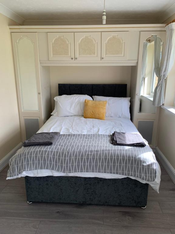 una camera da letto con un grande letto con due cuscini sopra di Large, Spacious 3 Bedroom Sleeps 6, Apartment for Contractors and Holidays in Lewisham, Greater London - 1 FREE PARKING SPACE & FREE WIFI a Londra