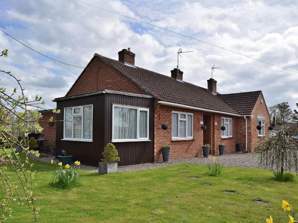 a brick house with a grass yard in front of it at Lenas Lodge in Birtsmorton