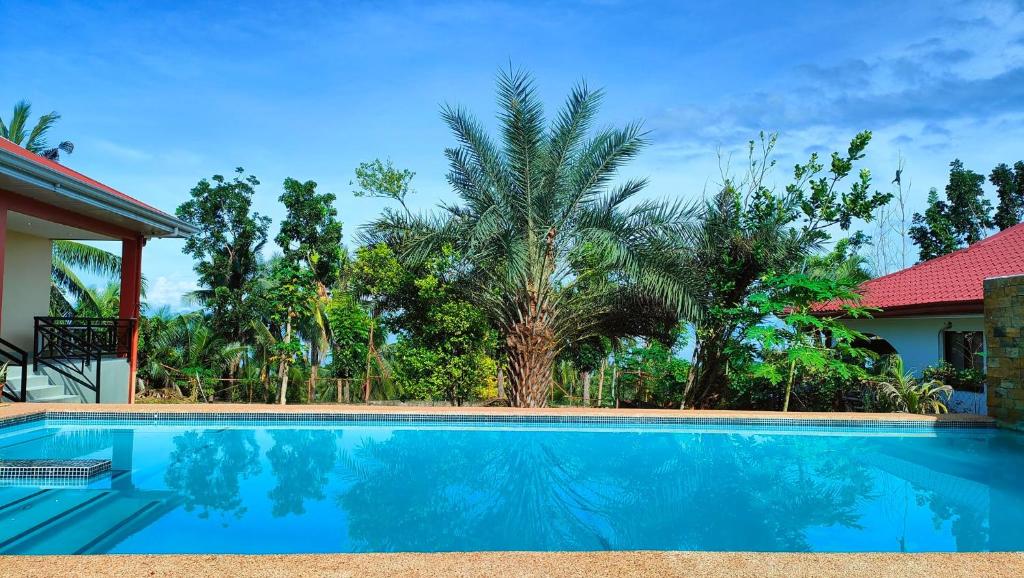 a swimming pool in front of a house with trees at SBG Resort Lambug in Badian