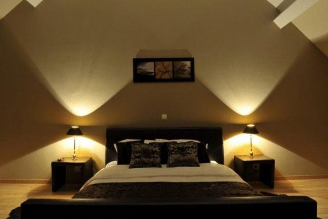 a bedroom with a large bed with two night lights at B&B Espace Tello in Jodoigne